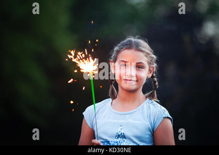 Portrait von Mädchen, dass Wunderkerze im Garten in der Dämmerung am Unabhängigkeitstag, USA Stockfoto