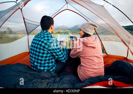 Paar im Zelt sitzen, trinken Sie heiße Getränke, Ergebnisse anzeigen Stockfoto