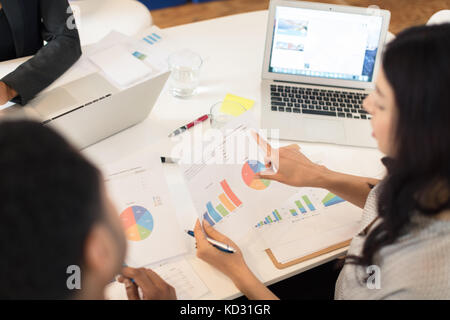 Geschäftsfrau auf Kreisdiagramme auf Tisch Stockfoto