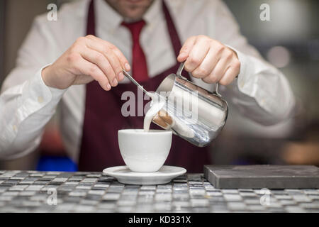 Kellner im Restaurant, gießen die Milch in der Kaffeetasse, mittlere Partie Stockfoto