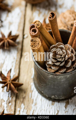 Weihnachten backen Zutaten Cinnamon Sticks verstreut Anis Sterne Walnüsse Kegel in Vintage kanne Kiefer auf Holz Hintergrund. festliche Grußkarte Poster. n Stockfoto