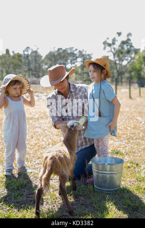 Mutter und zwei Kindern auf der Farm, mit der Flasche füttern junge Ziege Stockfoto