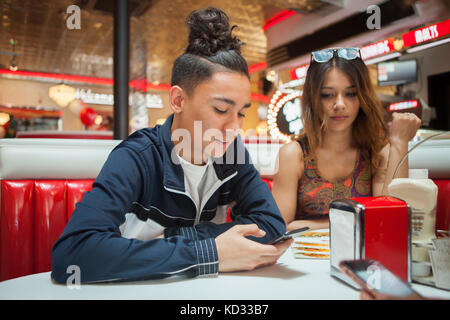 Junges Paar, in Diner sitzen, junge Mann an Smartphone suchen, Frau mit Gelangweilter Ausdruck Stockfoto