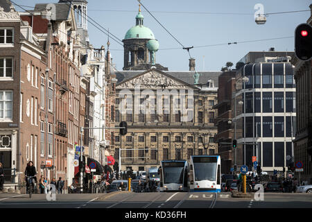 Verkehrs- und Straßenbahnen in der Raadhuisstraat in Amsterdam mit dem Königlichen Palast im Hintergrund Stockfoto