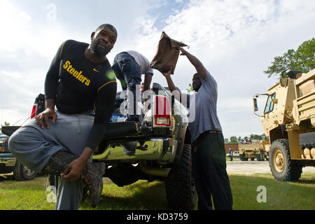 NFL-Spieler Clifton Geathers mit den Pittsburgh Steelers, nachdem er mit Hilfe von US-Soldaten bei der 1053. Transportation Company, South Carolina Army National Guard, in Brown's Ferry in der Nähe von Georgetown, South Carolina, 10. Oktober 2015 Besitz, der nicht durch die Flut zerstört wurde, in seinem Familienhaus zurückgebracht hat. Die South Carolina National Guard wurde aktiviert, um staatliche und County Notfallmanagement-Agenturen und lokale Ersthelfer zu unterstützen, da historische Überschwemmungen Grafschaften landesweit beeinflussen. Derzeit wurden mehr als 3,000 Mitglieder der South Carolina National Guard als Reaktion auf den Flo aktiviert Stockfoto