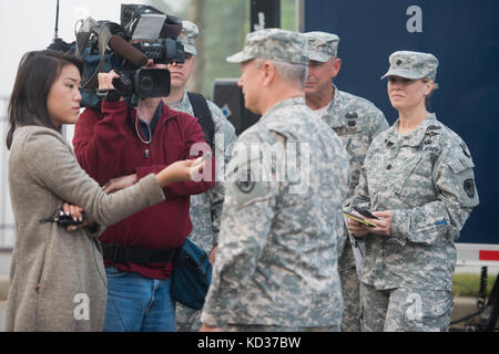 US Army LT. Col. Cindi King, South Carolina National Guard Director of Public Affairs, sieht Reporter interviewen Gen. Frank Grass, der Chef der National Guard Bureau, am Flussufer Kanal in Columbia, South Carolina, 14. Oktober 2015. Die South Carolina National Guard wurde aktiviert, um staatliche und County Notfallmanagement-Agenturen und lokale Ersthelfer zu unterstützen, da historische Überschwemmungen Grafschaften landesweit betroffen. Derzeit wurden mehr als 2,200 Mitglieder der South Carolina National Guard als Reaktion auf die Überschwemmungen aktiviert. (USA Air National Guard Foto von Tech. Sgt. Jorge I. Stockfoto