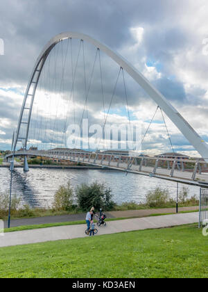 Eine Familie am nördlichen Ufer des Flusses Tees durch die Unendlichkeit Brücke für Fußgänger und Zyklus Kreuzung an der Stockton Stockfoto