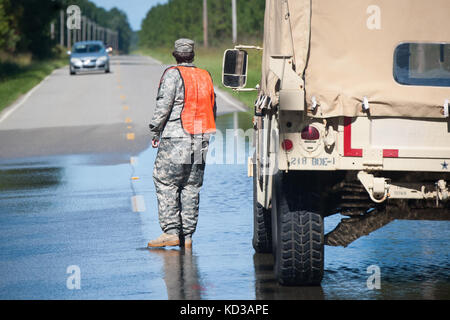 Us-Armee Pfc. ciara Todd, zu der 133 Military Police company in South Carolina Army National Guard bietet Hilfe und Traffic Control während einer Wiederherstellung des Fahrzeugs in Lee County, S.C. ÜLG zugewiesen. 6, 2015. die South Carolina National Guard mit Bundes-, Landes- und lokale Emergency Management Agenturen und Ersthelfer in Reaktion auf Hochwasser bedroht weite im Bereich zusammengeschlossen, um als Ergebnis der starken Regen. (U.s. Army National Guard Foto von Sgt. Brian Calhoun/freigegeben) Stockfoto