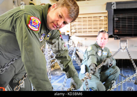 Senior Master Sgt. Matt youngerman, lademeister Betriebsleiter für die 315 Luftbrücke control Flug, sichert eine m1a1 sa Abram mit schweren Ketten an Bord einer C-17 vor dem Flug. Der South Carolina Army National Guard 1-118 th kombinierte Waffen Bataillon (Cab) in schweren Luftbrücke Operationen beteiligt, April 10-11, 2014 at Wright Army Airfield (waaf), hinesville Ga., die Gemeinsame, insgesamt Kraft zu demonstrieren, Fähigkeiten des s.c. army Guard und 315. Der US Air Force reserve airlift Wing. Soldaten und Piloten unisono arbeitete über zwei Tage zu laden und sichern Sie vier neue Die 1-118 th-Cab m1a1 sa abr Stockfoto