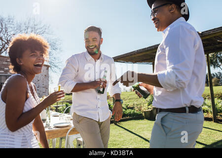 Lachende junge Menschen, die eine Party im Restaurant im Freien. Gruppe von Multiethnischen Freunde genießen Partei an einem sonnigen Tag. Stockfoto