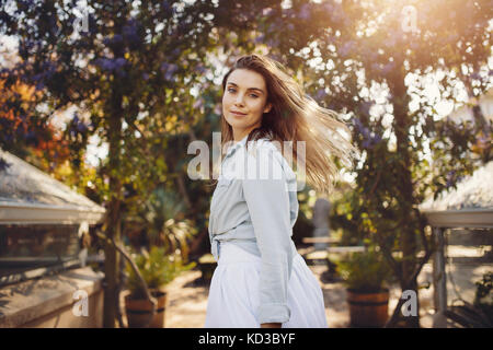 Porträt der schöne junge Frau in einem Park an der Kamera schaut. Junge Frau Mode Modell an einem Garten. Stockfoto