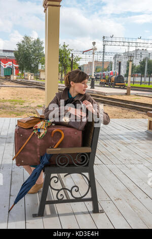 Porträt einer jungen Frau auf einer Bank sitzen. Warten auf den Zug im Bahnhof. Stockfoto