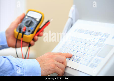 Ingenieur stellt die Parameter der industriellen Steuerung. Elektriker mit Hilfe von Industrial Tastatur Multimeter. Stockfoto