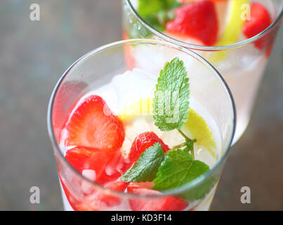 Zwei Gläser Obst Wasser mit frischen Erdbeeren, Zitrone und Minze über zerkleinertes Eis Stockfoto