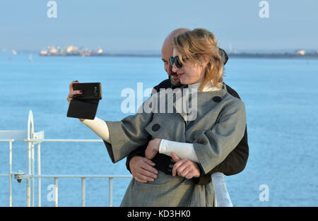 Ein junges Paar mit einem selfie Foto mit dem Meer im Hintergrund an der Southampton, Hampshire, UK. Stockfoto