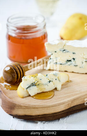 Blauschimmelkäse mit frischen Birnen und Honig auf rustikalen Schneidbrett, Käseplatte serviert. Stockfoto