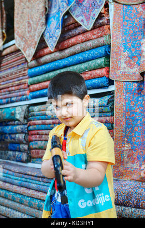 Provinz Fars, Shiraz, Iran - 19. April 2017: Ein unbekannter Mann, ca. 10 Jahre alt, spielt mit einer Kalaschnikow Spielzeug Automat in der Textil- Shop des c Stockfoto