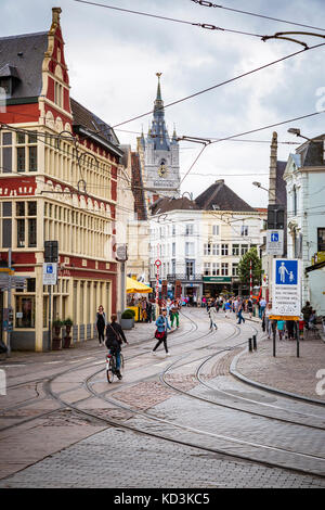 Gent, Belgien - 22. Juni 2016: vertikale Bild der Innenstadt in Gent in einem bewölkten Tag mit gebogenen Straßenbahn Schienen, Häuser, Geschäfte, Menschen und eine Kirche in Stockfoto