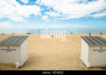 Breites Bild der Strand mit Leuten, Umkleidekabinen am Strand, Möwen an einem sonnigen Tag mit Wolken. Oostende, Belgien. Stockfoto