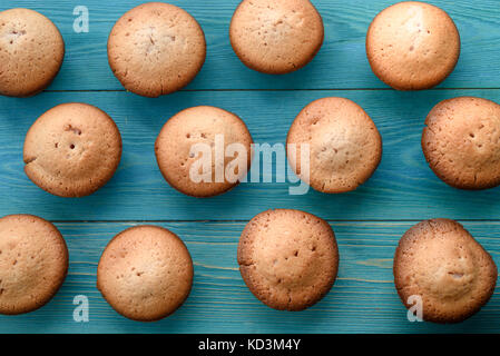 Frische Muffins auf einem Schneidebrett auf einer hölzernen blauen Hintergrund. Hintergrund. Textur des frisch gebackenen Muffin. close-up. Makro Stockfoto