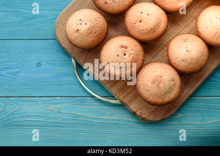 Frische Muffins auf einem Schneidebrett auf einer hölzernen blauen Hintergrund. Hintergrund. Textur des frisch gebackenen Muffin. close-up. Makro Stockfoto