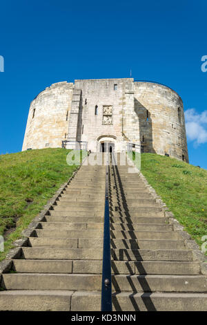 Treppen führen zu Clifford's Tower auf einem Gras bedeckten Hügel mit blauem Himmel Stockfoto