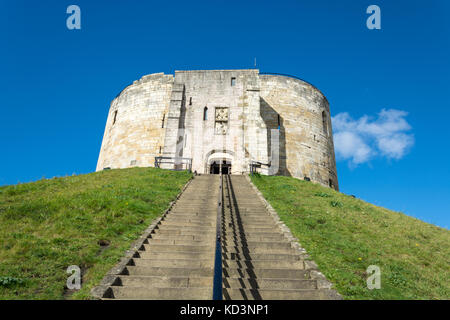 Treppen führen zu Clifford's Tower auf einem Gras bedeckten Hügel mit blauem Himmel Stockfoto