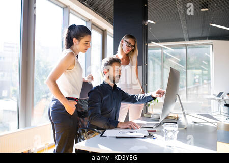 Drei Geschäftsleute diskutieren am Arbeitsplatz. Zwei Frauen und ein Mann im Büro arbeiten zusammen. Stockfoto