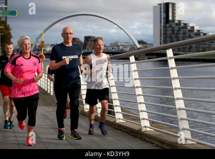 Der stellvertretende erste Minister John Swinney (Mitte) leitet die „Conference Mile“ entlang des Flusses Clyde mit Hannah Bardell MP (links) und Ivan McKee MSP (rechts), nachdem sie an der Konferenz der Scottish National Party im SEC Center in Glasgow teilgenommen haben. Stockfoto