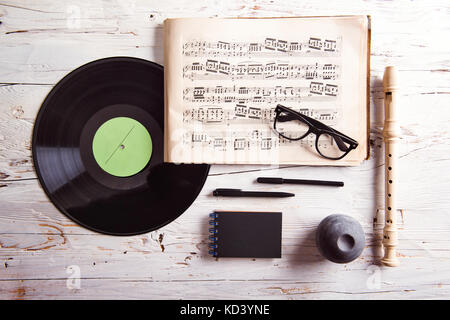 Schreibtisch mit Musikschulutensilien. Studio-Aufnahme auf weißem Holzhintergrund. Stockfoto