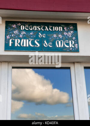 Rustikales französisches Restaurant Werbung sign 'degustation de fruits de Mer' (schmecken die Früchte des Meeres) mit blauem Himmel und Hafen in Fenster Stockfoto