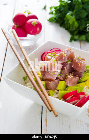 Hawaiian tuna poke Schüssel mit Avocado, Radieschen und Sesam auf weißem Holz- Hintergrund Stockfoto