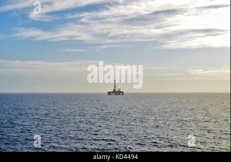 Eine stationäre Bohrinsel, stehend auf einem eigenen in der Ferne am Horizont, an einem bewölkten Tag, vor der Küste von Malta, der Maltesischen Inseln, Mittelmeer Stockfoto