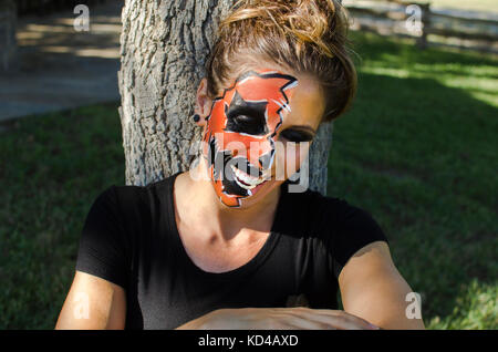 Frau in Jack-o-Lantern Gesicht Farbe sieht glücklich aus und festlich für die Halloween Herbst Urlaub. Stockfoto