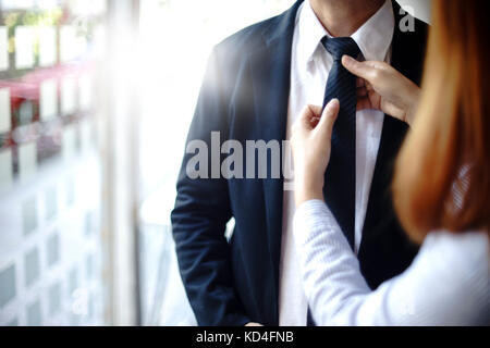 Geschäftsmann vorbereiten zu gehen, um das Projekt und die Assistant Hilfe Krawatte anpassen zu präsentieren Stockfoto