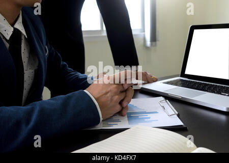 Kaufmann und Kauffrau im Team vorhanden Daten in Tabelle in dunklen Ton Büro mit Computer Bildschirm Freistellungspfaden. Stockfoto