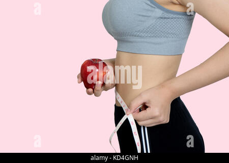 Schlanke Frau mit Apfel Obst auf rosa Hintergrund mit Freistellungspfad isoliert Stockfoto