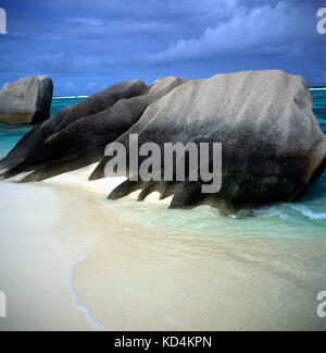 Granitfelsen von Meer Sandstrand stürmischen Himmel geprägt, Anse Source D'Argent, La Digue Island, Seychellen Stockfoto