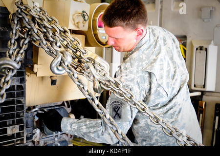 Us-Armee Pfc. Salbei beadling, ein m1 armor Crewman, sichert eine m1 mit schweren Ketten vor dem Flug. Der South Carolina Army National Guard 1-118 th kombinierte Waffen Bataillon (Cab) in schweren Luftbrücke Operationen beteiligt, April 10-11, 2014 at Wright Army Airfield (waaf), hinesville Ga., die Gemeinsame, insgesamt Kraft zu demonstrieren, Fähigkeiten des s.c. army Guard und 315. Der US Air Force reserve airlift Wing. Soldaten und Piloten unisono arbeitete über zwei Tage zu laden und vier neue Die 1-118 th-Cab sa m1a1 Abrams Kampfpanzer sichere auf vier US Air Force c-17-Transportflugzeuge für Transpo Stockfoto