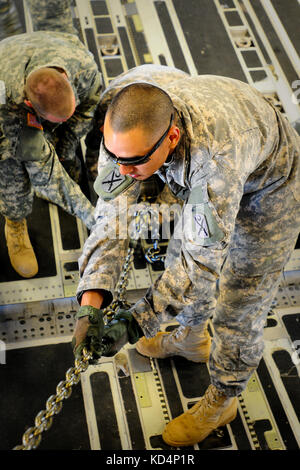 Us-Armee Sgt. Rudy Uribe, ein 19 k, m 1 armor Crewman, sichert eine m1a1 sa Abram mit schweren Ketten an Bord einer C-17 vor dem Flug. Der South Carolina Army National Guard 1-118 th kombinierte Waffen Bataillon (Cab) in schweren Luftbrücke Operationen beteiligt, April 10-11, 2014 at Wright Army Airfield (waaf), hinesville Ga., die Gemeinsame, insgesamt Kraft zu demonstrieren, Fähigkeiten des s.c. army Guard und 315. Der US Air Force reserve airlift Wing. Soldaten und Piloten unisono arbeitete über zwei Tage zu laden und vier neue Die 1-118 th-Cab sa m1a1 Abrams Kampfpanzer auf vier US Air Force sichere c Stockfoto