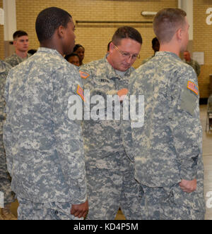 Befehl Sgt. maj. William bostic, 228Th Theater taktische Signal Brigade command Sergeant Major, Offiziell begrüßte sieben Soldaten in die 228Th ttsb, indem Sie die Einheit Patch auf den Uniformen der Soldaten während einer patching Zeremonie am Bluff Road Armory in Kolumbien gehalten, s.c., Oct. 24, 2015, die Zeremonie bedeutete die Soldaten die Durchführung grundlegender Ausbildung und Erweiterte individuelle Trainings- und offiziell zu ihrem neuen Einheiten begrüßt. (U.s. Army National Guard Foto von 1 Lt. jessica Donnelly/freigegeben) Stockfoto