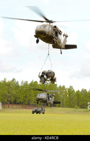 Soldaten der US-Armee mit dem 351st Aviation Support Battalion, S.C. Army National Guard, verbinden einen Humvee und Wasserbüffel zu Black Hawks, um Schlingladeroperationen in Fort Jackson, 13. Juli 2014 zu üben. Die Ausbildung ist Teil der Vormobilisierungsvorbereitung der Einheit für ihren bevorstehenden Einsatz in Kuwait. (USA Foto der Armee-Nationalgarde von Sgt. Brian Calhoun/Veröffentlicht) Stockfoto