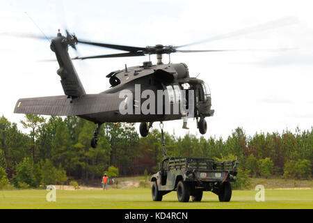 Soldaten der US-Armee mit dem 351st Aviation Support Battalion, S.C. Army National Guard, verbinden einen Humvee und Wasserbüffel zu Black Hawks, um Schlingladeroperationen in Fort Jackson, 13. Juli 2014 zu üben. Die Ausbildung ist Teil der Vormobilisierungsvorbereitung der Einheit für ihren bevorstehenden Einsatz in Kuwait. (USA Foto der Armee-Nationalgarde von Sgt. Brian Calhoun/Veröffentlicht) Stockfoto