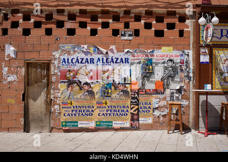 Straßenszene mit Plakaten an einer gemauerten Ladenfront in Alcázar de San Juan in Spanien Stockfoto