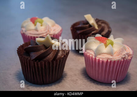 Erdbeer und Schokolade cupcakes durch heiße Schokolade mit Sahne und Schokolade abstauben begleitet. Stockfoto