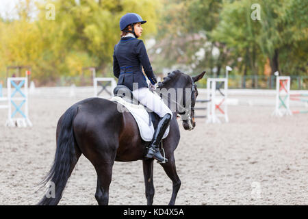 Junge Reiterin Frau auf Bay Horse Aufwärmen vor erweiterte Dressur Test bei Pferderennen. reiterfall Hintergrund mit Kopie Raum Stockfoto