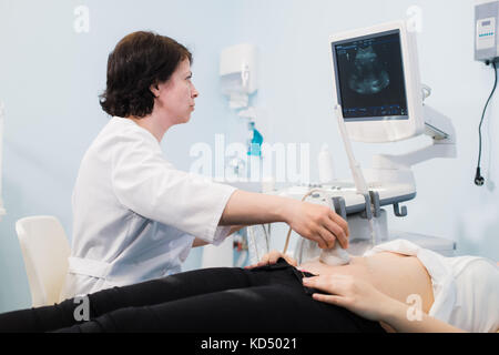 Schwangere Frau, die Ultraschallbehandlung im Krankenhaus Stockfoto