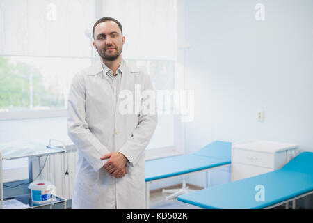 Lächelnd gutaussehenden Arzt im Krankenhaus.. bei Kamera schaut. Stockfoto