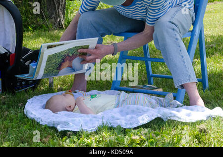 Wenig Leser: Baby erhält die Chance, das Buch zu sehen, Gemeinschaftsgarten, Maine, USA Stockfoto