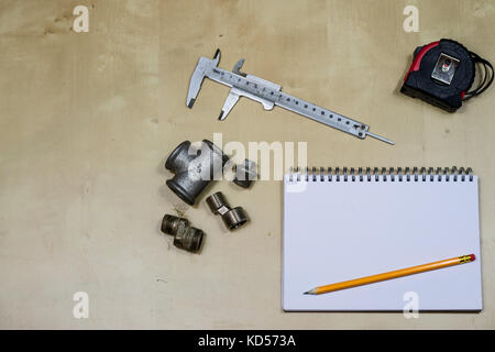 Materialien, Zubehör und Ersatzteile für Hydraulik. Noten- und Messwerkzeuge auf dem Workshop Tabelle. Holztisch. Stockfoto